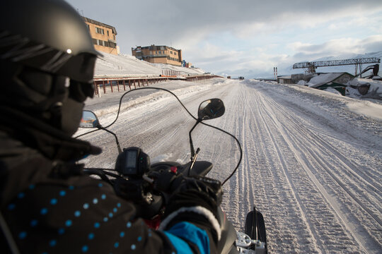 Over the shoulder view of person on snowmobile on snowy road, Svalbard, Norway