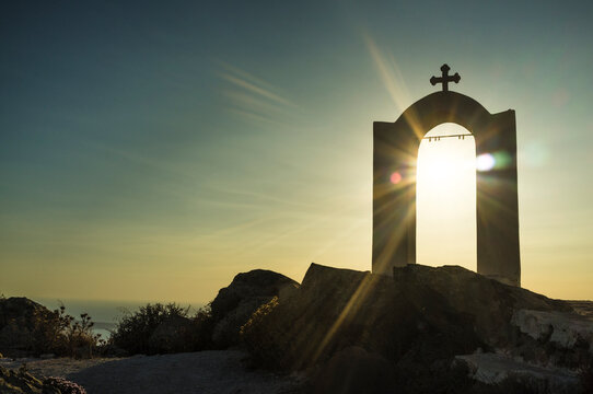 View of religious arch and cross at sunset, Oia, Santorini, Greece