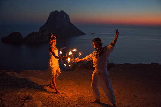 Couple dance with fire sunset, Ibiza, Es Vedra rock in the background