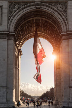 Sunlit view of french flag and Arc de Triomphe, Paris, France