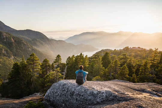 Man sitting on rock, looking at view, Stawamus Chief, overlooking Howe Sound Bay, Squamish, British Columbia, Canada