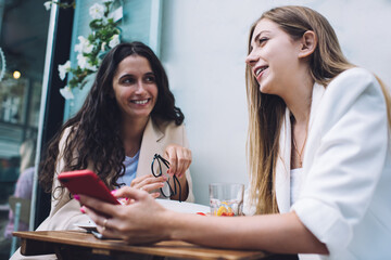 Happy women sharing news in outdoor cafe