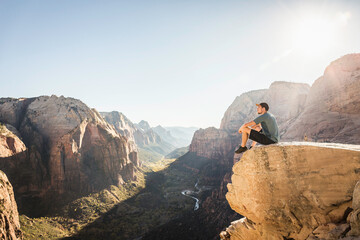 Man hiking Angels landing trail, sitting on rock, Zion National Park, Utah, USA
