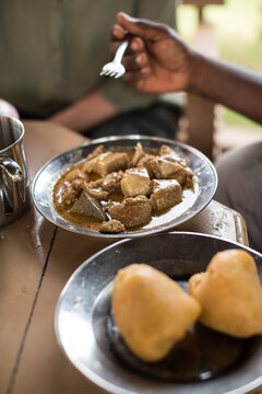 Person eating traditional African meat dish, mid section, Cotonou, Littoral, Benin, Africa