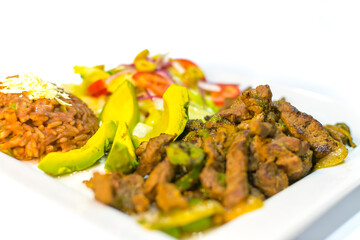 plate with meat, beans, avocado and tortillas toasted in squares to eat with beer and lemon. lovely black background.