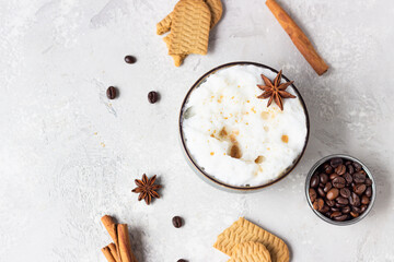 Cup of black coffee or cappuccino with milk foam decorated with anise star and cinnamon stick on light grey table with gingerbread cookies and roasted coffee beans. Lifestyle and coffee concept.