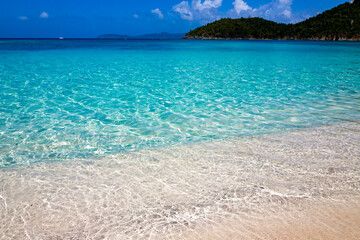 Crystal clear water laps the white sand of Hawksnest Bay Beach.