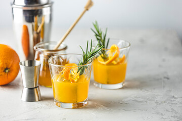 Honey bourbon cocktail with rosemary simple syrup or homemade whiskey sour cocktail drink with orange and rosemary. Decorate orange peel. Light concrete surface.