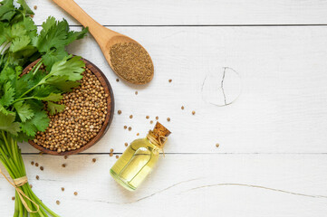 Glass bottle of coriander essential oil with coriander powder and fresh cilantro leaves on rustic...