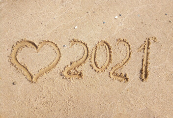 The concept of a New year. Heart and numbers 2021 in the sand. Summer beach holidays . The message is handwritten