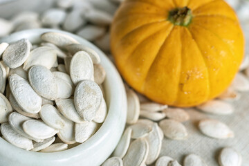 White pumpkin seeds in a white bowl.