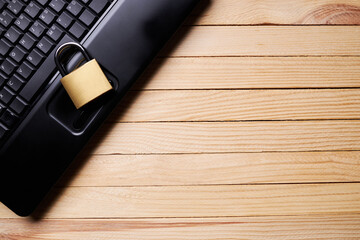 privacy data protection. above view for a black laptop and golden padlock over wooden desk. cyberspace safety technology concept