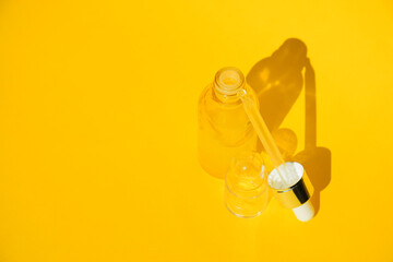 Collagen facial serum in clear yellow bottle with soft shadow on yellow background. Eessence oil, vitamin C or spa concept.