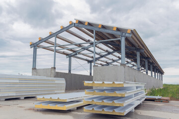 Metal frame of the building with a sandwich panel of insulation on the wall. Construction of a new industrial building. Modern Insulation of the walls of the building panels of insulation.