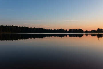 Sunrise over lake on a calm, peaceful morning, with forest in afar