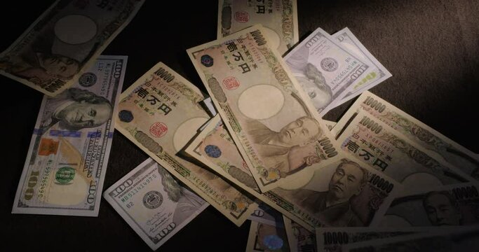 U.S. Hundred Dollar Bills And Japanese Ten Thousand Yen Bills Dropped Onto Table