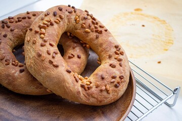 Artistic composition in natural light. Large homemade cedar nut bagels on a wooden plate and metal grill. In the background there are traces of cooking (focus is deliberately blurred)