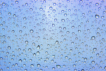 Rain drops on car glass. Gray blue background, toned