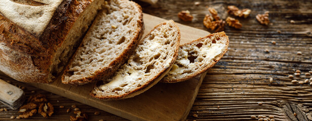 Traditional sourdough bread sliced smeared with butter baked in a craft bakery on a wooden table...