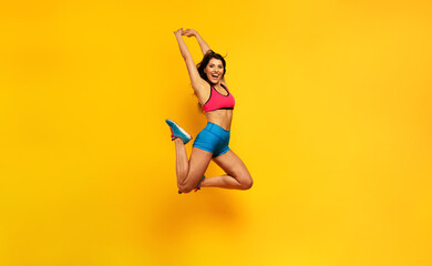 Sport woman jumps on a yellow background. Happy and joyful expression.