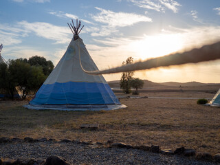 Caseta de campaña de estilo tipi indio en un bosque durante la puesta de sol