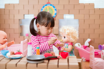 young  girl pretend play babysitting with baby doll at home