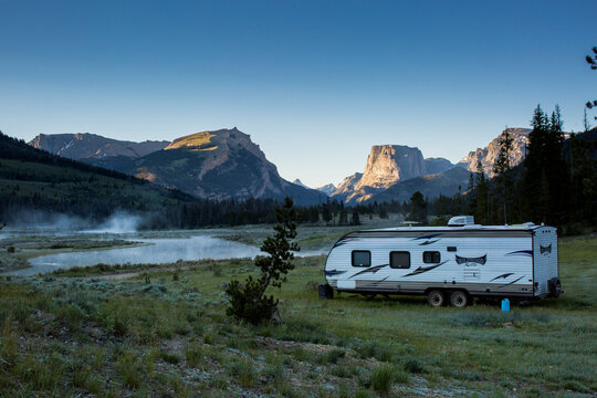 Travel trailer parked on grass against mountains