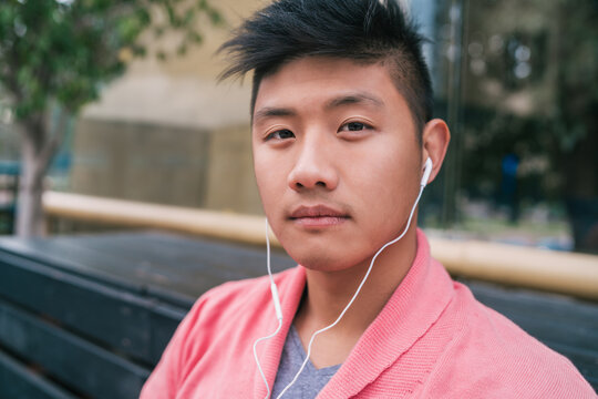 Asian man listening to music with earphones.