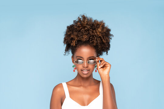 Afro woman wearing sunglasses and earrings.