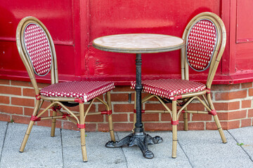 Two empty dining chairs either side of a table outside a restaurant or cafe