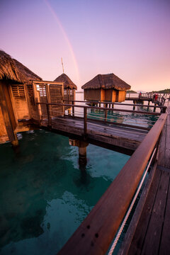 View of rainbow over water bungalows during sunset