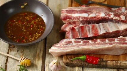 Selective focus. Macro. Raw pork ribs on a board and rib marinade in a bowl. Cooking BBQ ribs.