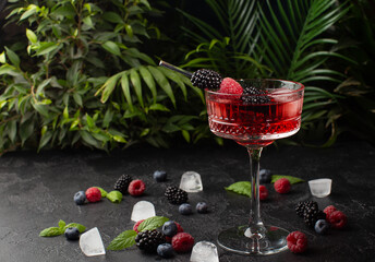 Fresh berries cocktail with raspberry,blackberry,mint and ice with tropical plants on...