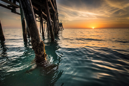 Fototapeta View of wooden pier in sea during sunset
