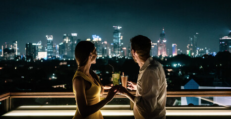 Couple having a drink on roof terrace overlooking the city
