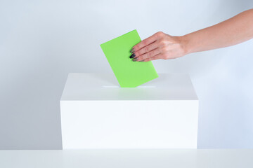 Voting in elections. A woman hand drops a green ballot into the ballot box. The public referendum....