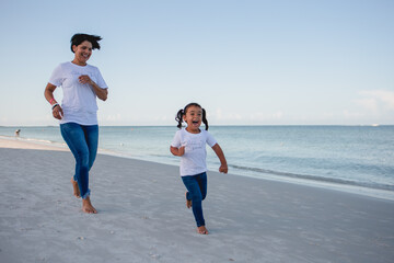 Fototapeta premium Mom and daughter on the beach running around and having fun stock photo royalty free 