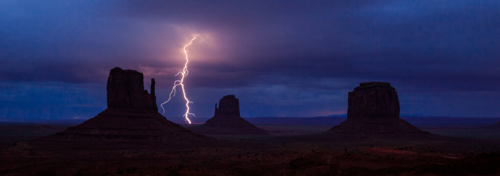 Lightning strikes between mittens in monument valley at dawn