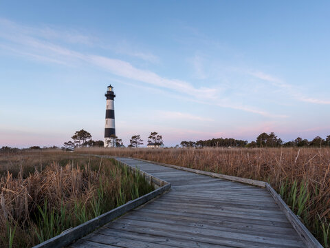Wooden boardwalk leading to Bodie Island Lighthouse during sunrise
