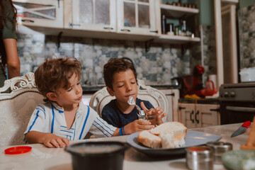 A beautiful caucasian  mother in a dress with her two sons is standing in the kitchen during breakfast. Family time