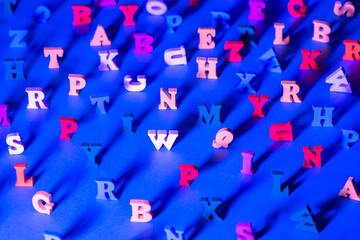Three-dimensional Latin letters on a blue table. Background of Latin letters in a chaotic state. Learning the alphabet, the concept of education.