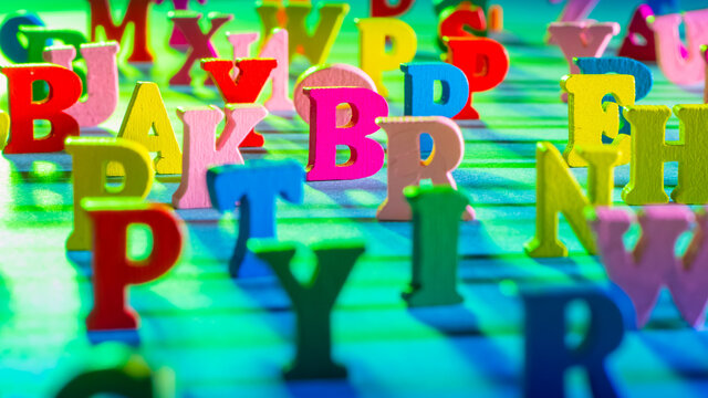 The letters of the Latin alphabet stand on a green background. Colorful learning concept. English letters in a chaotic order with focus in the center. Background from letters of the English alphabet.