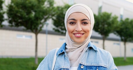 Portrait of young Arabic beautiful woman in traditional headscarf smiling happily to camera. Close...