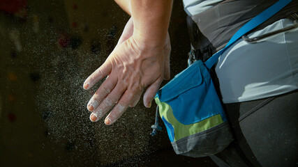 CLOSE UP: Woman training at a climbing gym applies magnesium to her hands.