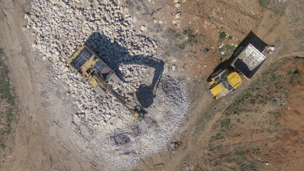 TOP DOWN: Industrial excavator crushing rocks and turning them into gravel.