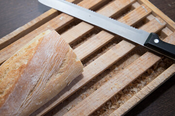 Loaf of bread cut on a wooden board with the bread knife after cutting bread.