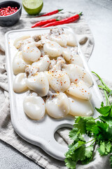 Fresh cuttlefish with chili pepper and parsley on a cutting Board. Gray background. Top view