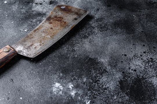 Meat cleaver on old scratched black  texture.  Dark background. Top view. Copy space