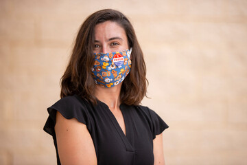 Caucasian woman wearing a fabric mask with cartoon puppy dog design and an I Voted Today sticker on the mask
