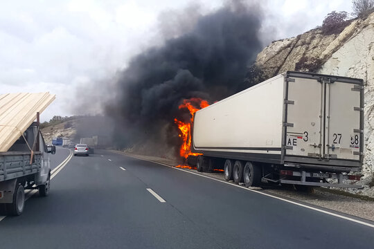 Burning truck on the road. cab of the truck is on fire.